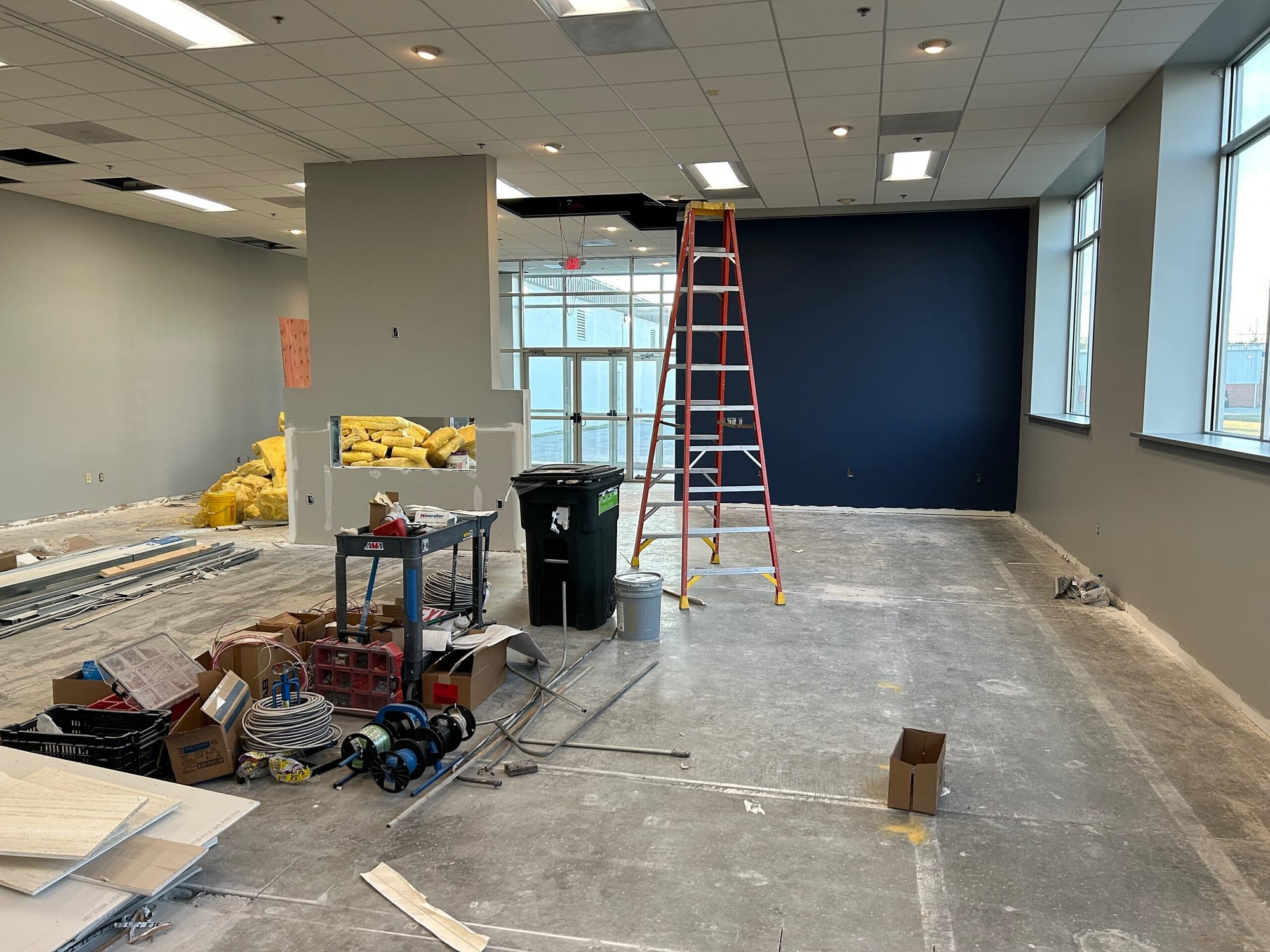 photo of construction in progress in the new showroom with ladders, equipment, a freshly painted wall, and a fireplace in progress